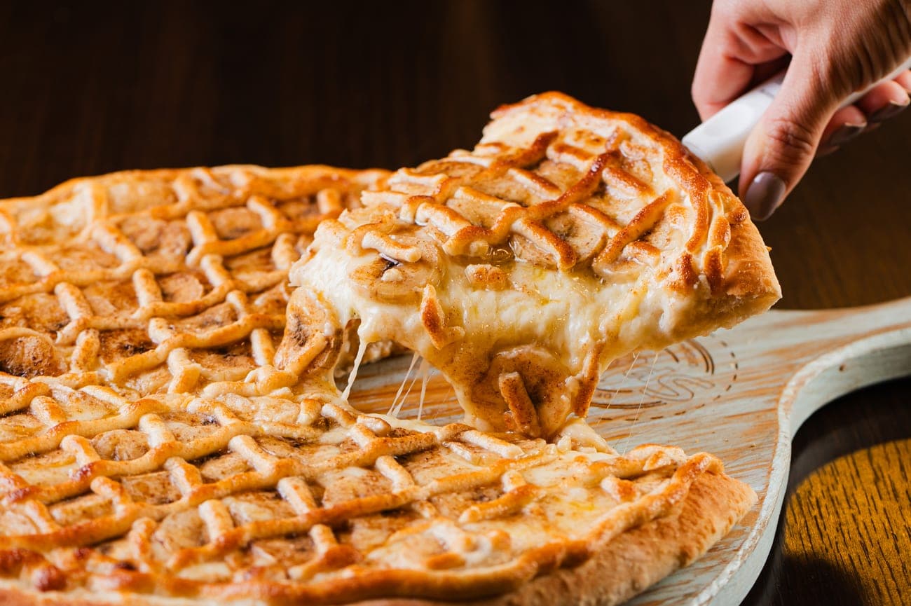 Fatia de pizza de queijo dourado sendo servida